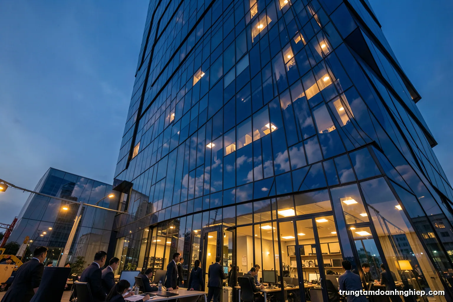 Low angle view of a modern glass office tower in Hanoi at dusk, warm lights glowing in windows, reflections of clouds on the facade, calm blue and amber palette